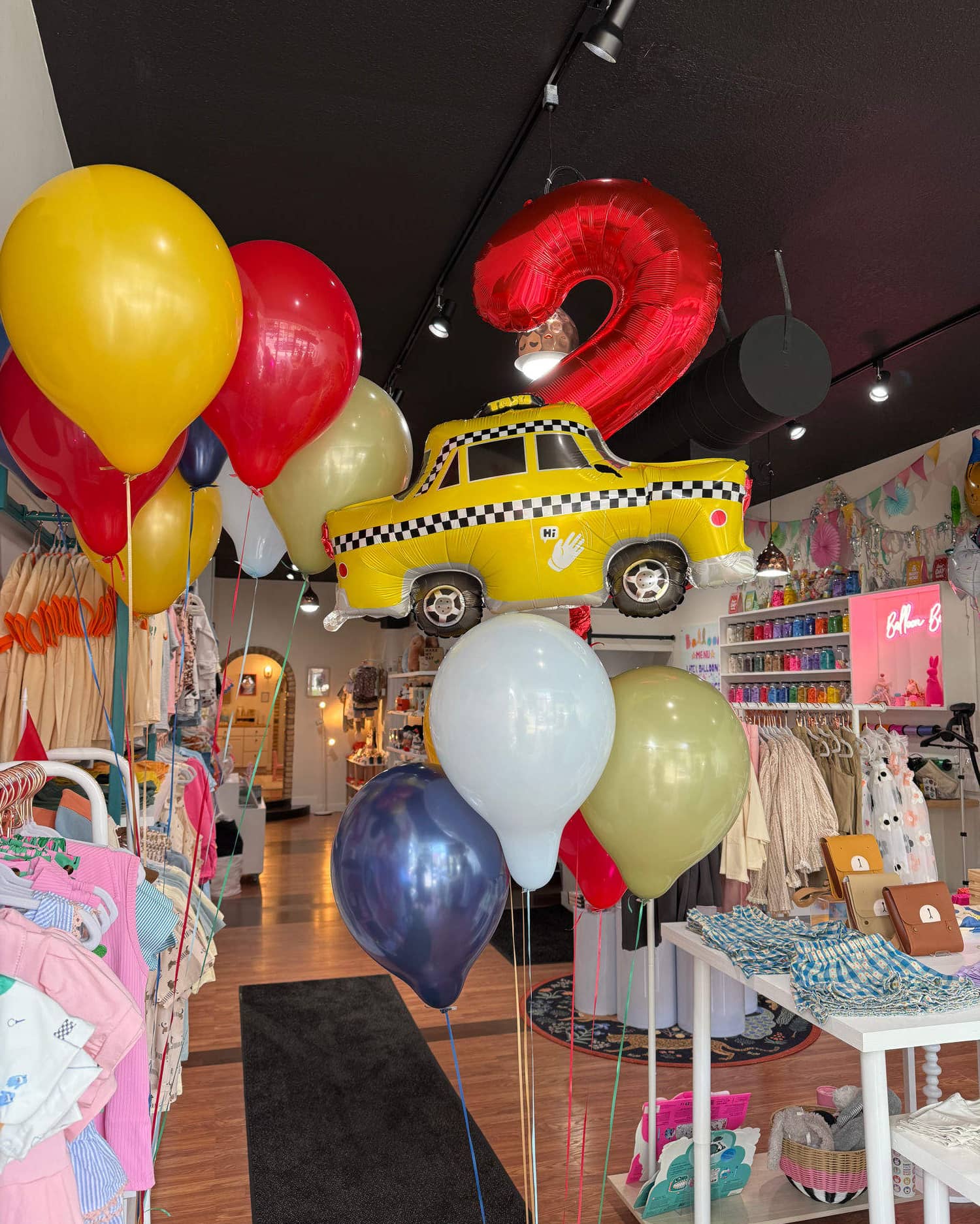 A finished bouquet standing in the middle of the shop: a big red foil number two and a checkered yellow taxi riding over yellow, red, navy and sage latex