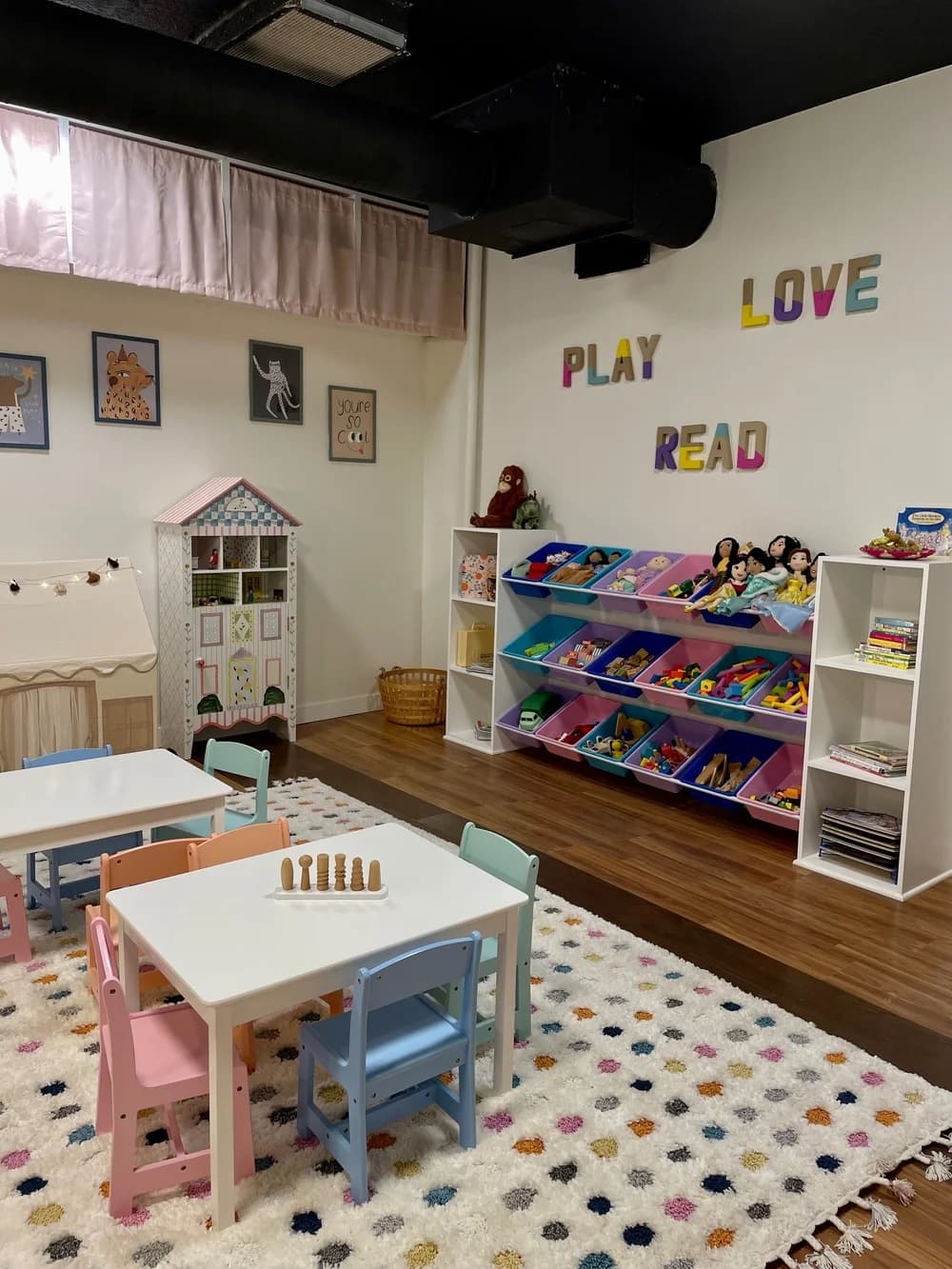 Toy shelves and small tables under the PLAY LOVE READ wall art