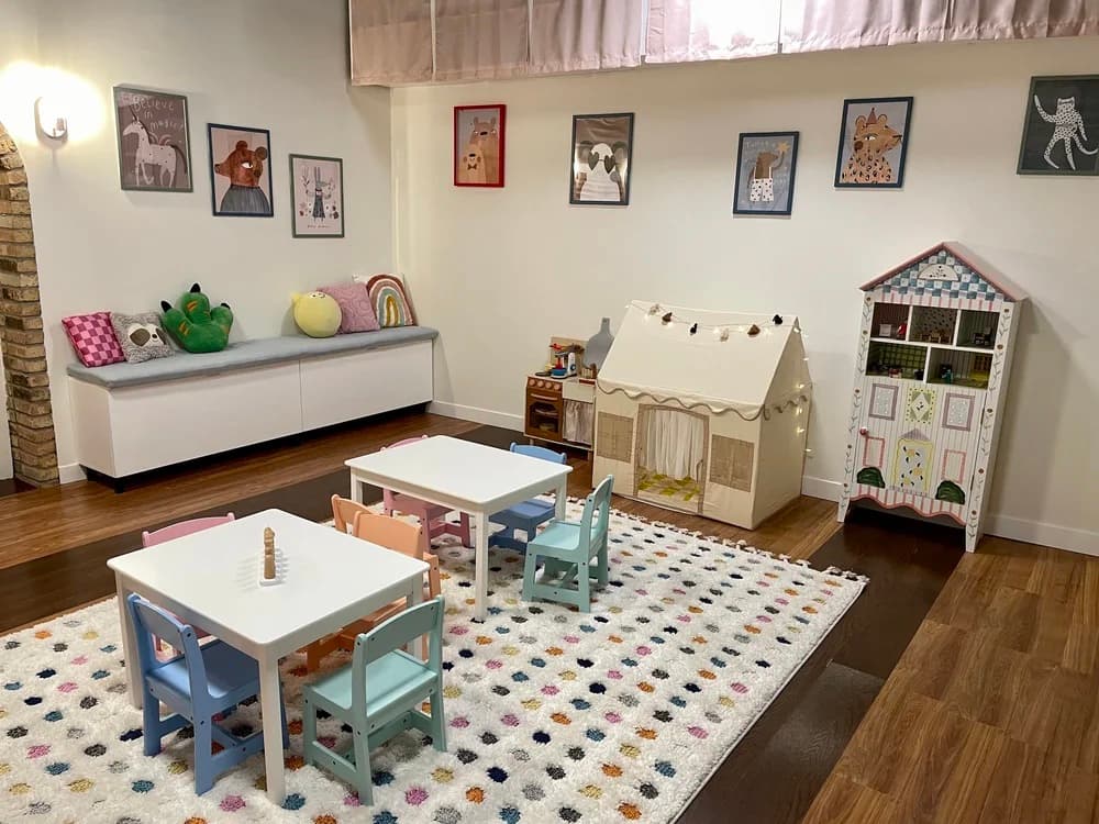 Play tent on a dotted rug, with stuffed animals on a low shelf